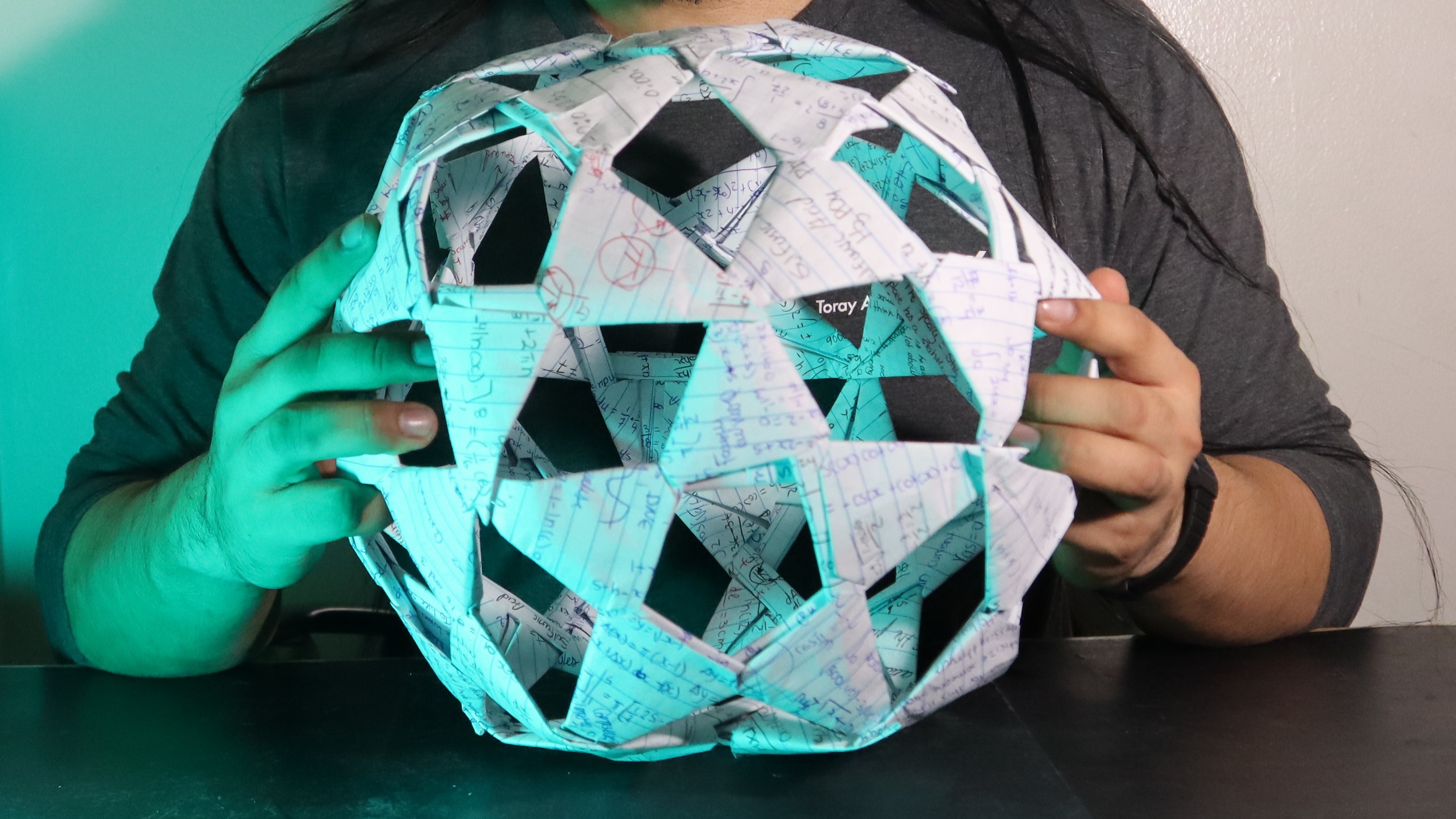 The finished paper sculpture being held with both hands to show its scale.