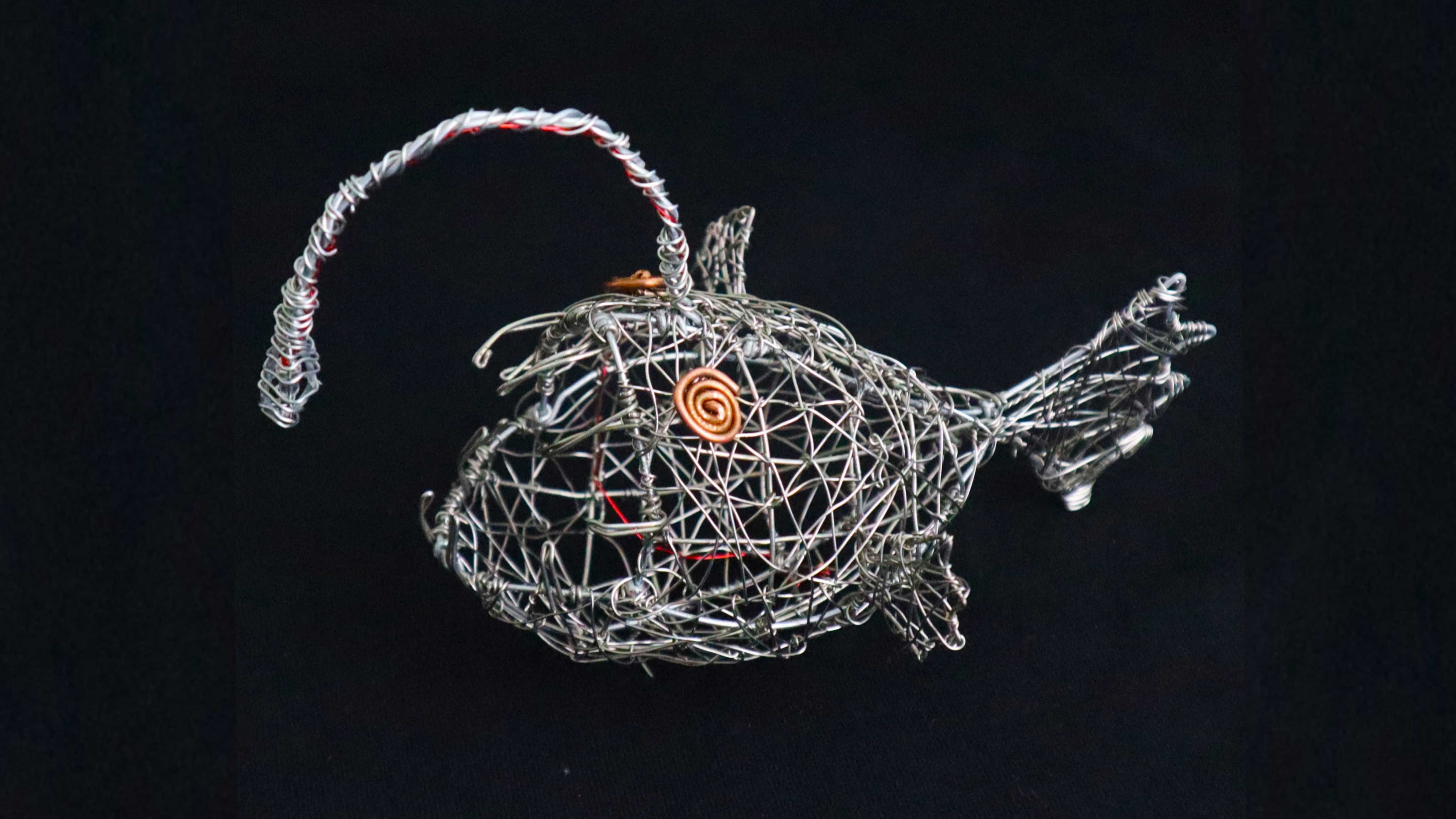 Side view of the wire anglerfish sculpture showing its woven wire structure.