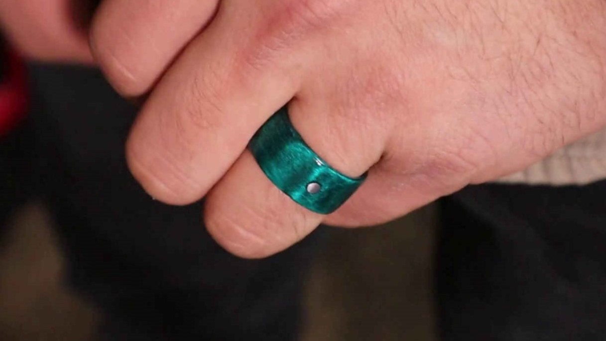 A green ring worn on a one finger showing the mark which helps with orienting the ring.