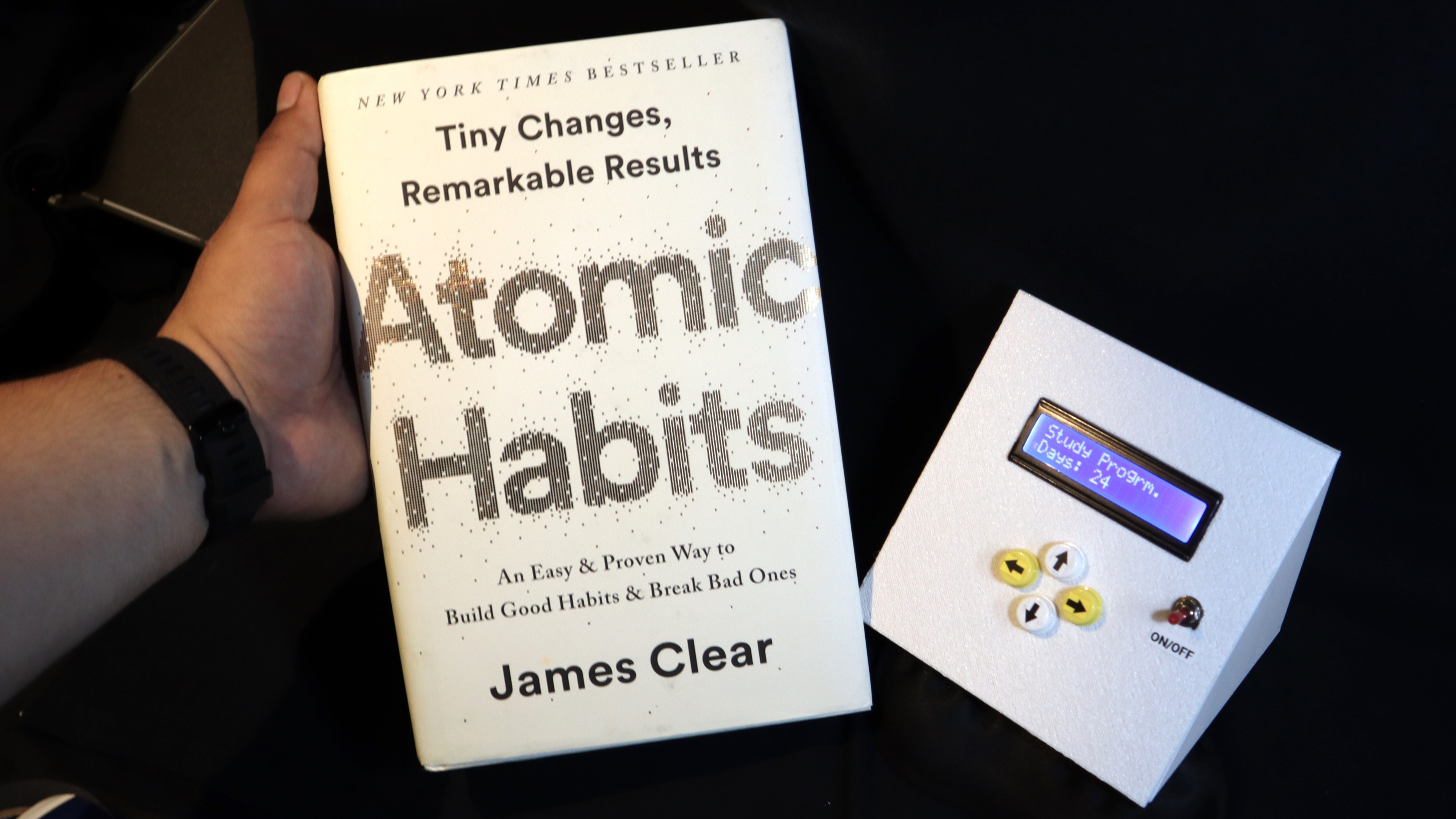 Holding the book Atomic Habits by James Clear.
